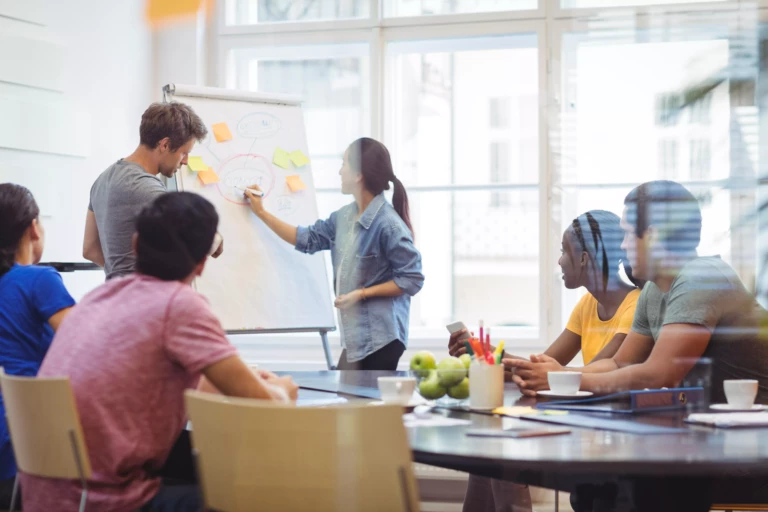 business-executives-discussing-with-their-colleagues-whiteboa